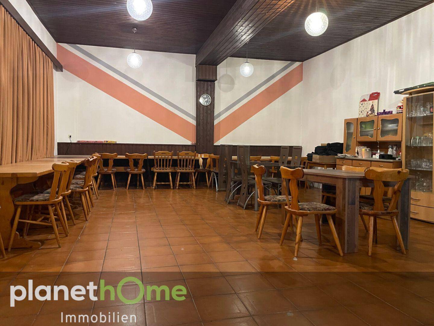 Großer Speisesaal mit zahlreichen Holztischen und Stühlen unter einer Holzdecke.