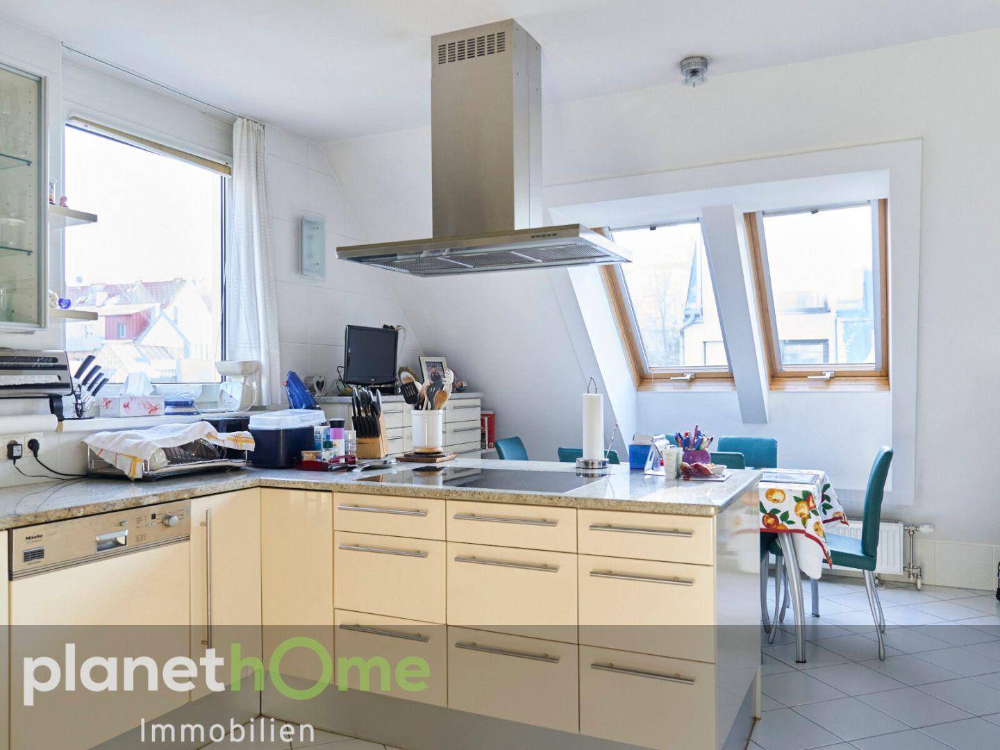 Nahaufnahme der Küche mit Kücheninsel, Kochfeld und Fenster mit Ausblick.