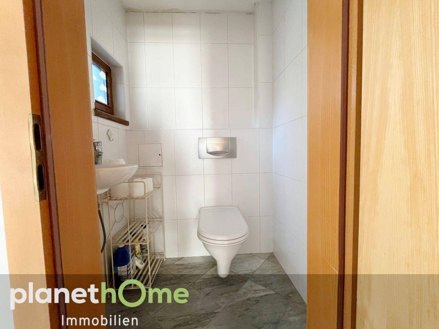 Kleines Gäste-WC mit wandhängendem WC, Waschbecken und Fenster.