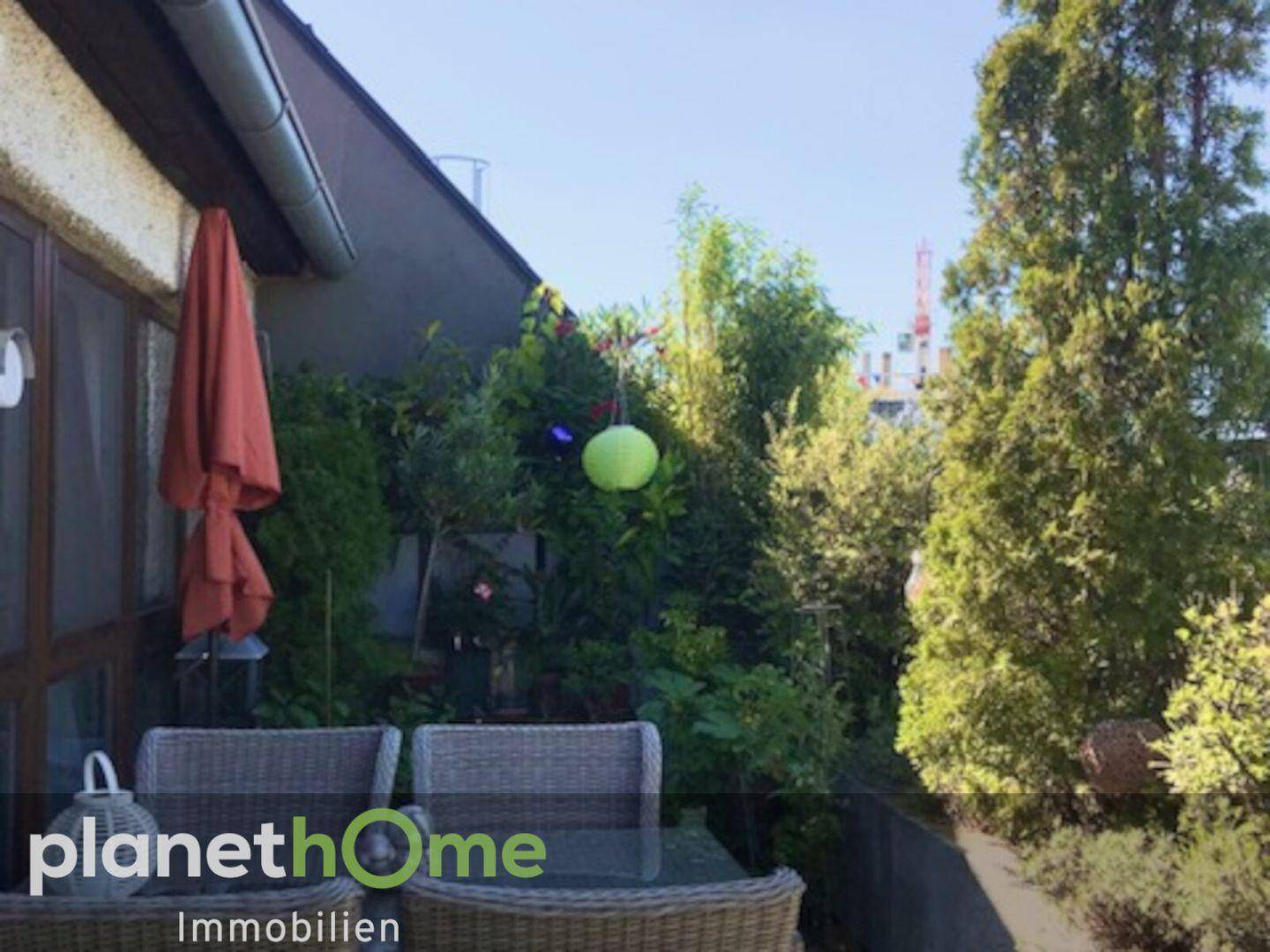 Gemütlicher Außenbereich auf der Terrasse mit Korbmöbeln und üppiger Bepflanzung.