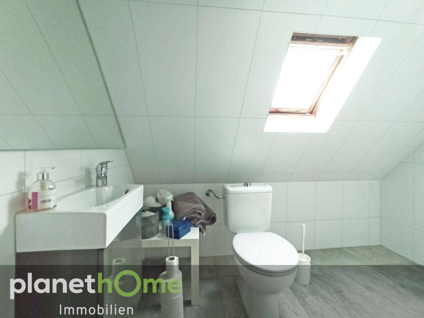 Modernes Badezimmer im Dachgeschoss mit Dachfenster, WC und Waschbecken.