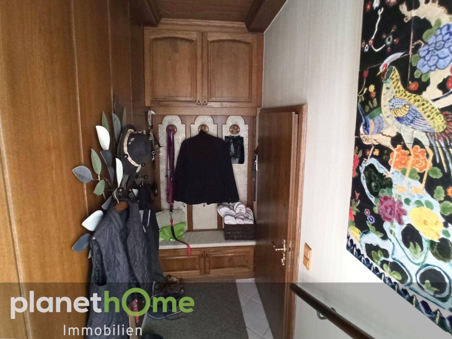 Eingangsbereich mit Garderobe, Holzverkleidung und dekorativem Wandteppich.