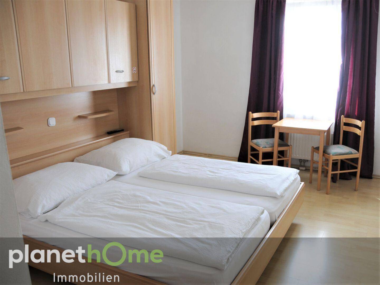Gemütliches Schlafzimmer mit Doppelbett, Holzmöbeln und einem kleinen Tisch am Fenster.