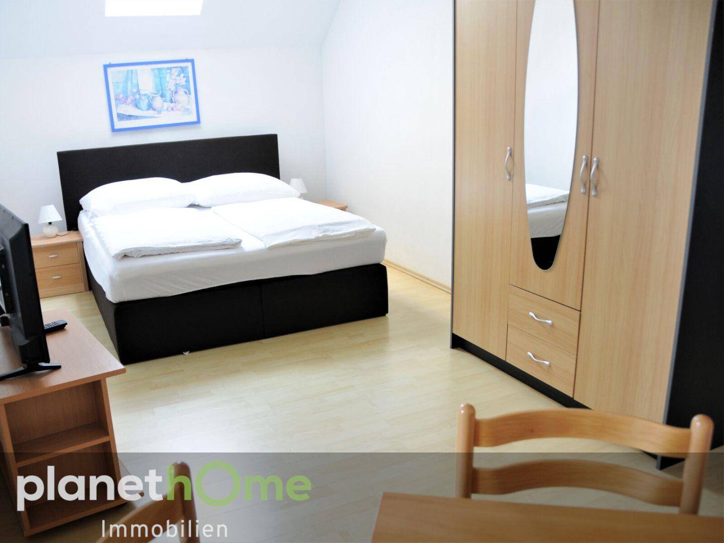 Modern eingerichtetes Schlafzimmer mit Doppelbett, Kleiderschrank und hellem Laminatboden.