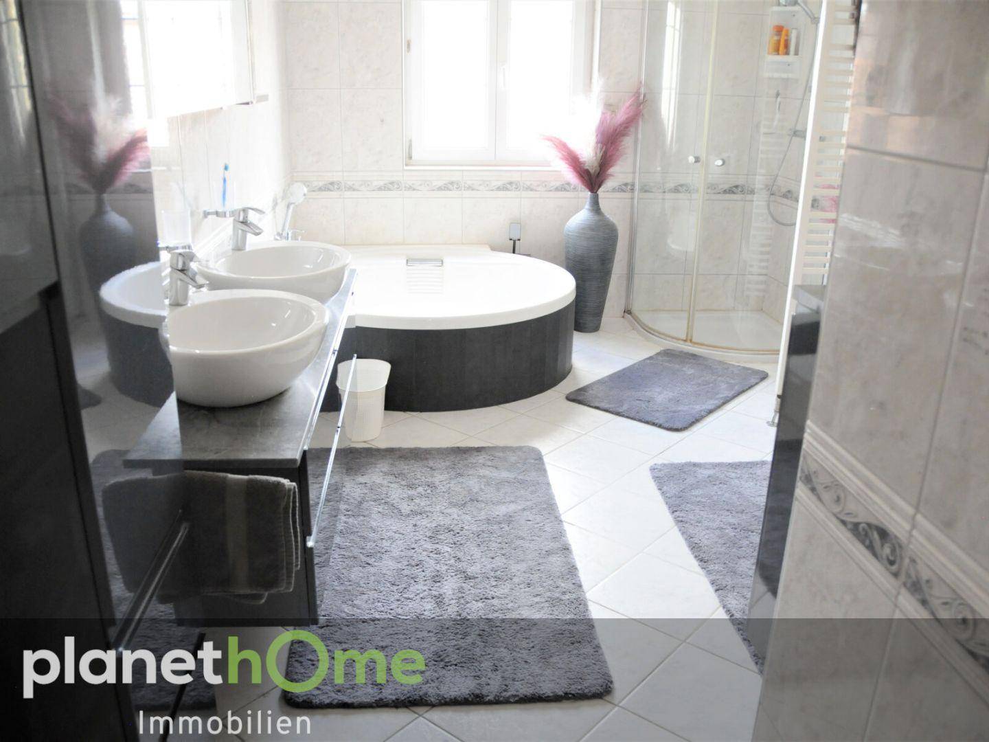 Modernes Badezimmer mit runder Badewanne, zwei Waschbecken und einer Duschkabine.