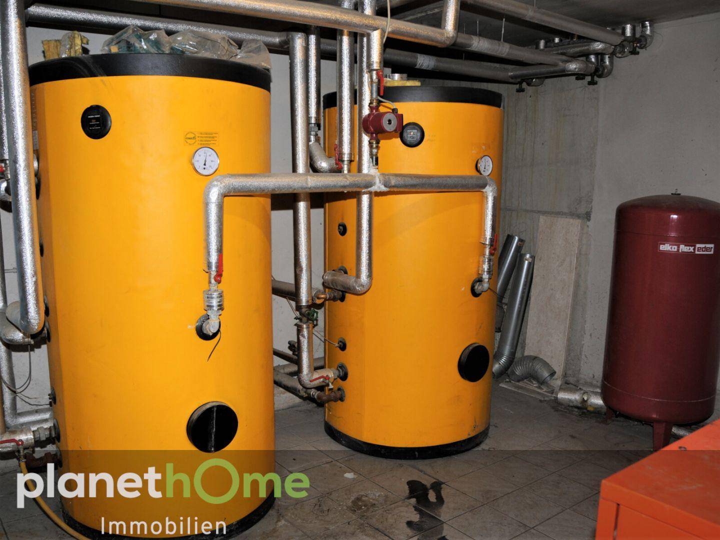 Heizungsraum mit großen gelben Warmwasserspeichern und komplexen Rohrinstallationen.