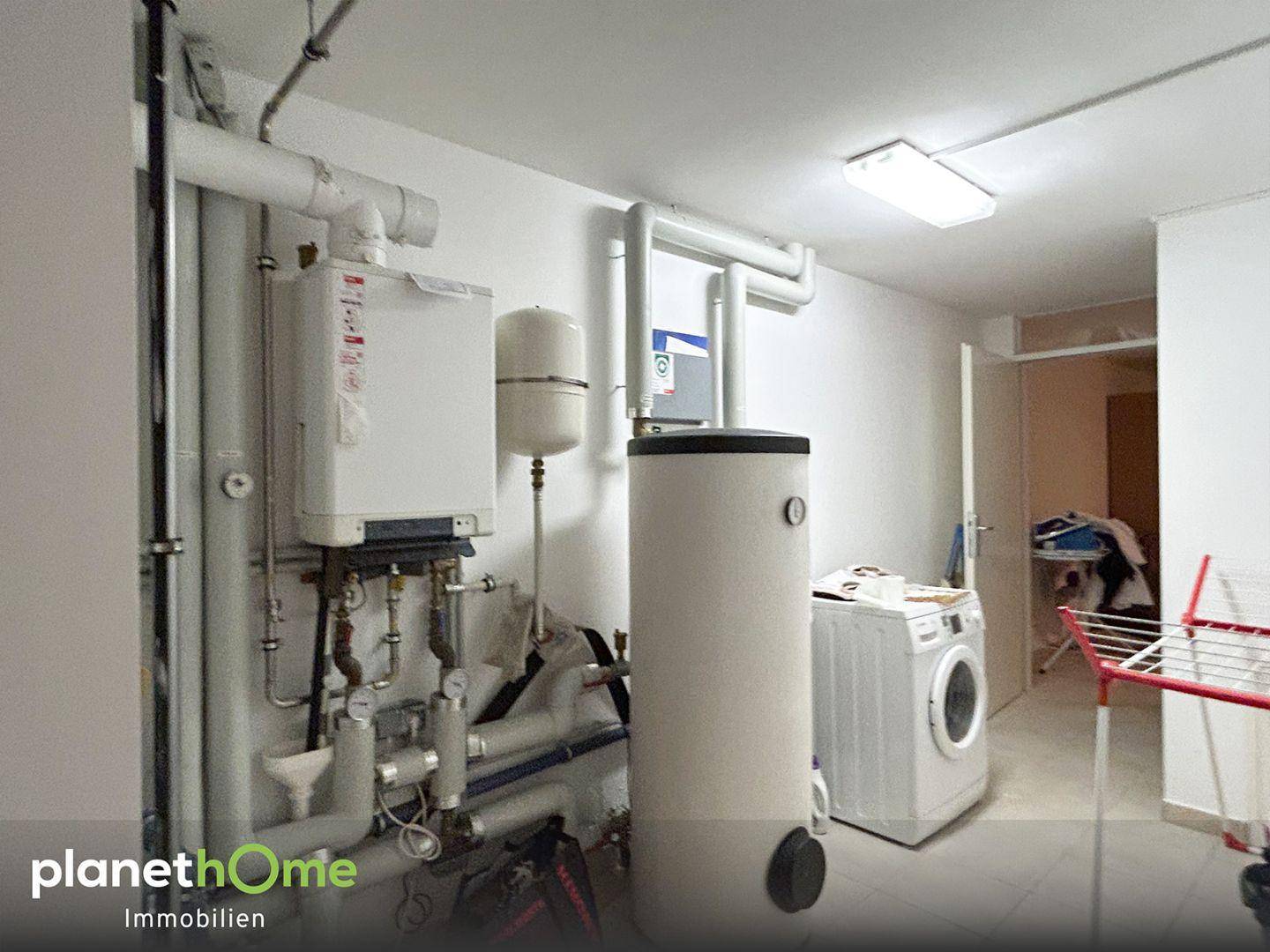 Funktionaler Hauswirtschaftsraum mit Heizungsanlage, Warmwasserspeicher und Waschmaschine.