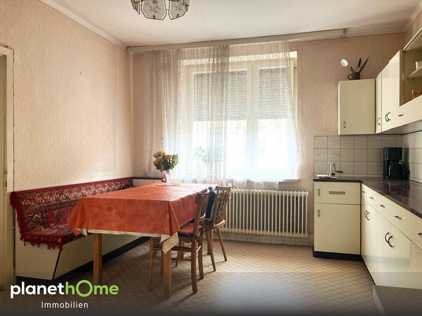 Gemütliche Küche mit einer Eckbank, Esstisch und einem großen Fenster, das viel Licht hereinlässt.