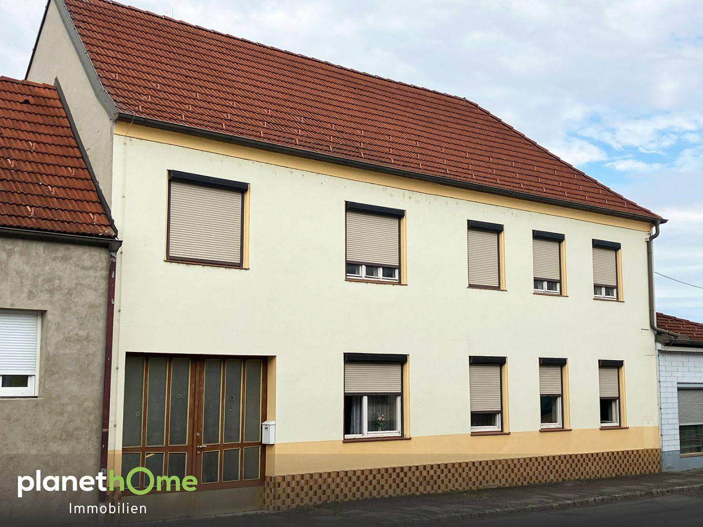 Vorderansicht des Wohnhauses mit mehreren Fenstern und heruntergelassenen Rollläden.