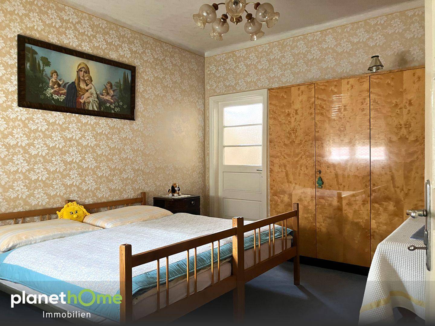 Schlafzimmer mit floraler Tapete, einem Doppelbett und einem großen Kleiderschrank.