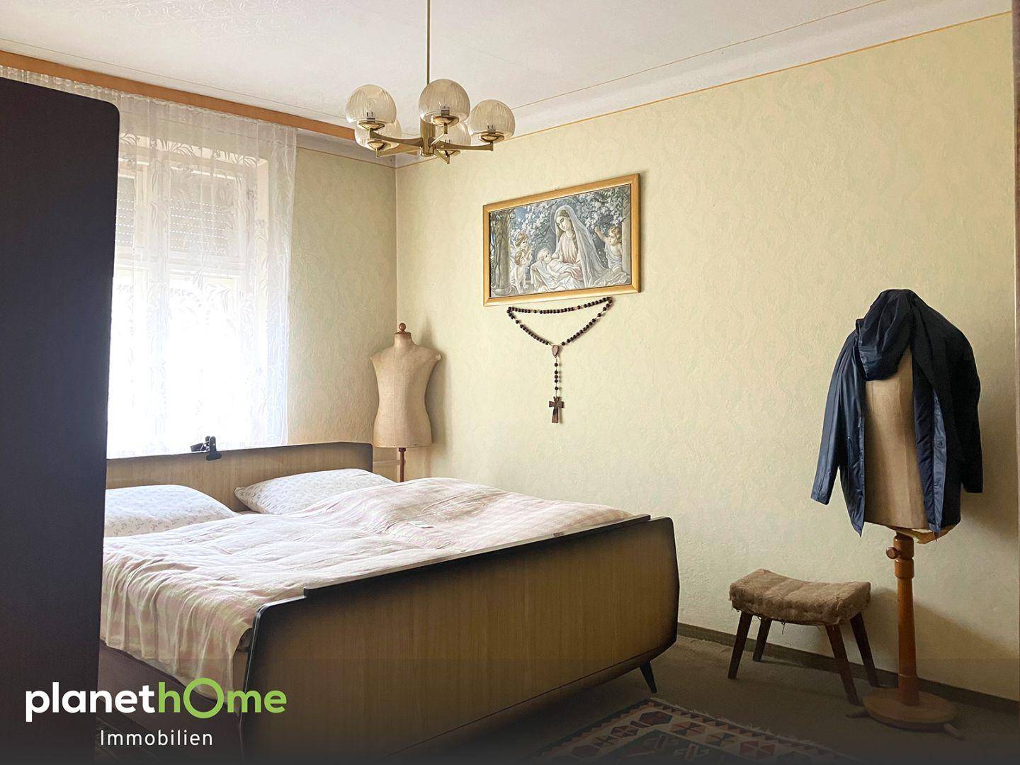 Schlafzimmer mit einem Doppelbett, schlichter Einrichtung und einem Fenster für Tageslicht.