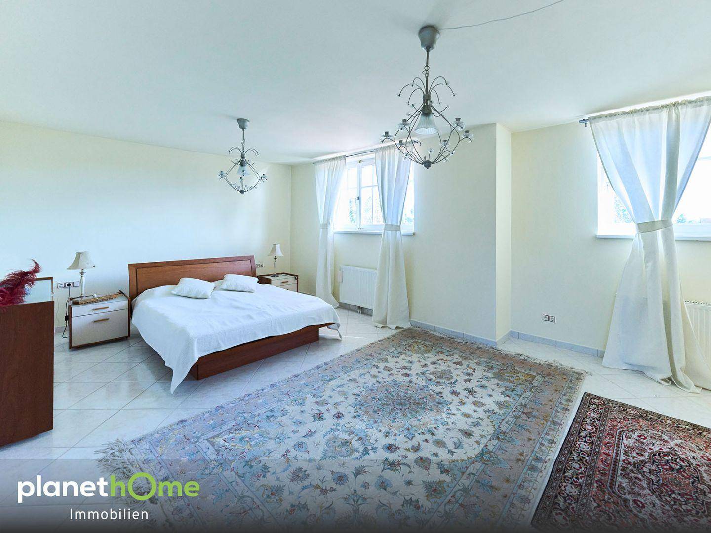 Geräumiges Schlafzimmer mit Doppelbett, Fliesenboden und zwei großen Fenstern.