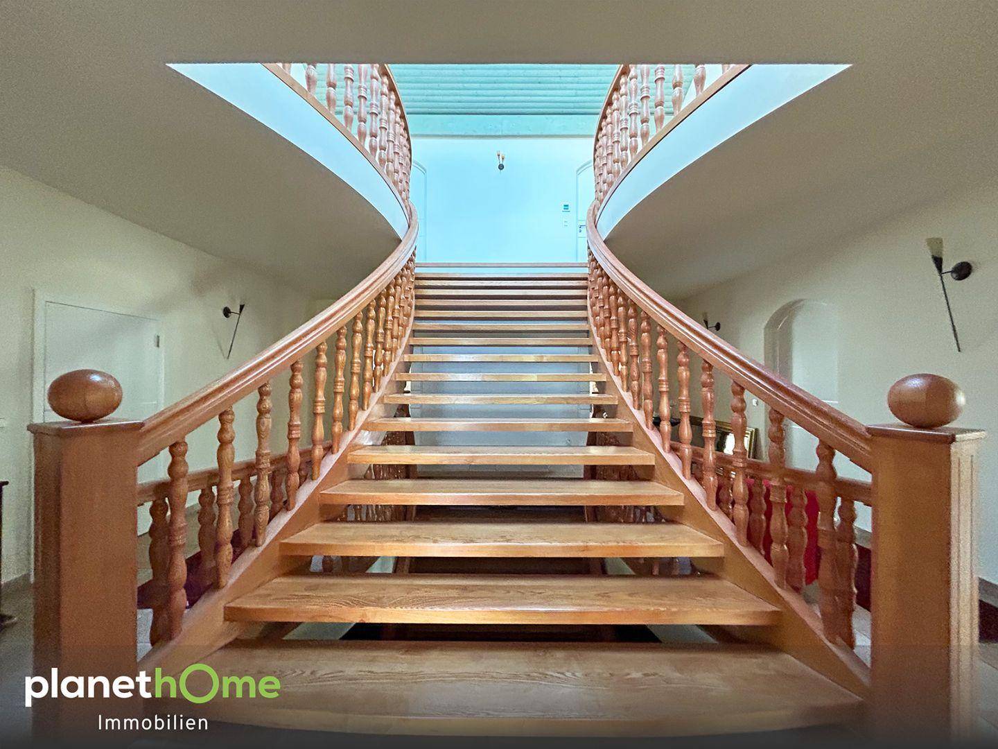 Elegante Holztreppe mit geschwungenem Geländer und Oberlicht im Eingangsbereich.