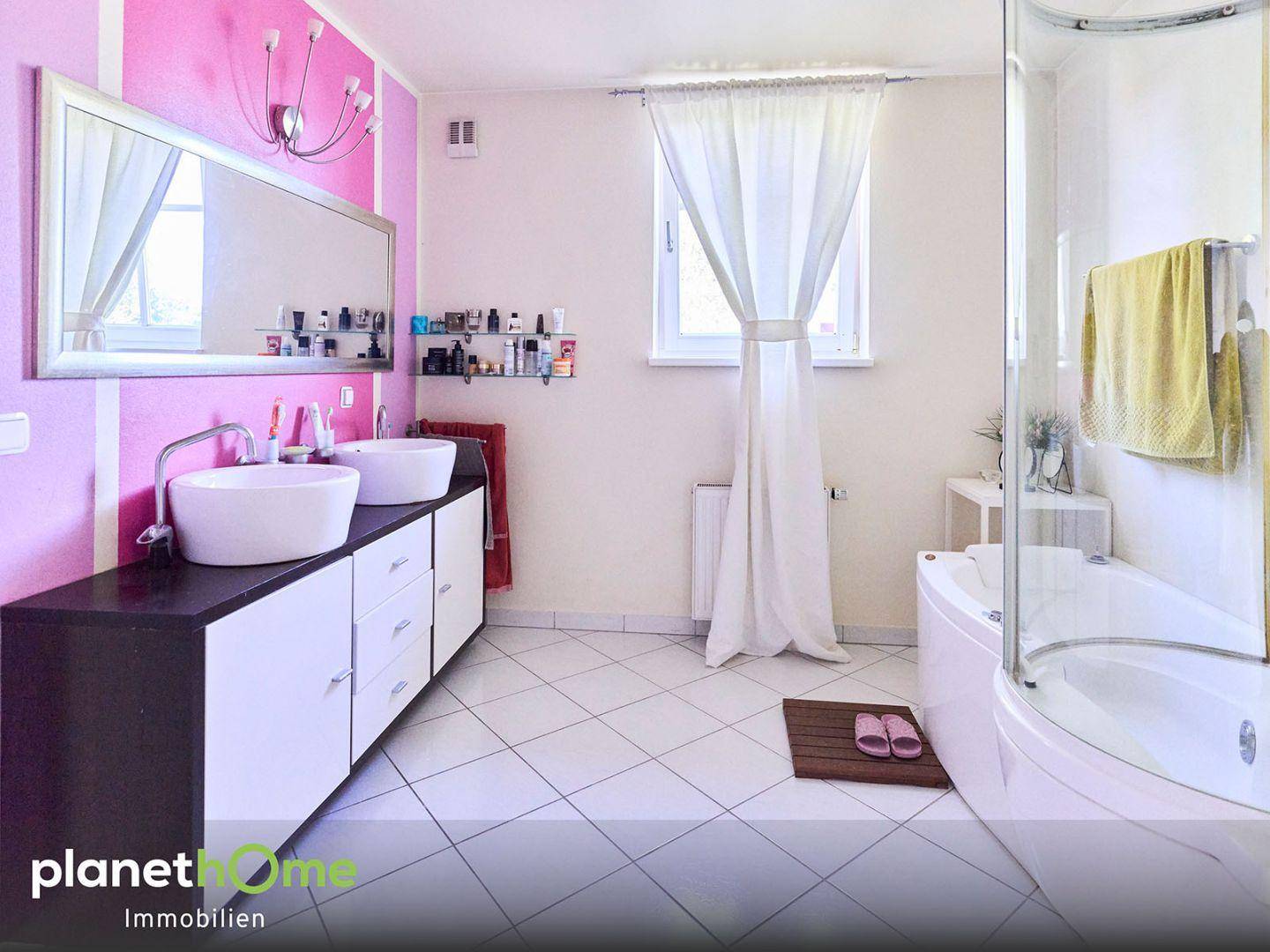 Modernes Badezimmer mit Doppelwaschbecken, Badewanne und pinkfarbener Akzentwand.