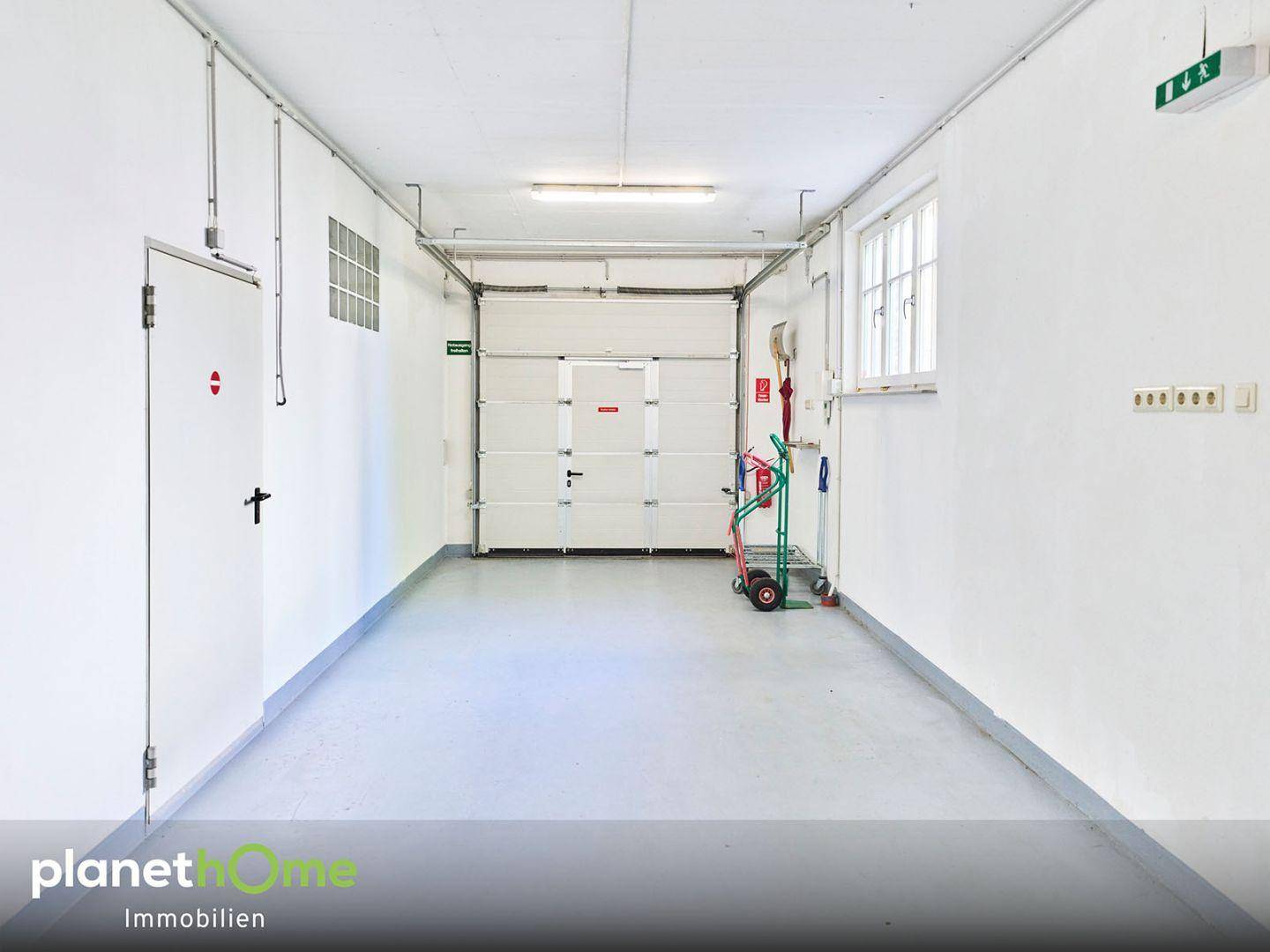 Geräumige Garage mit Rolltor, Fenster und viel Platz für Fahrzeuge und Lagerung.