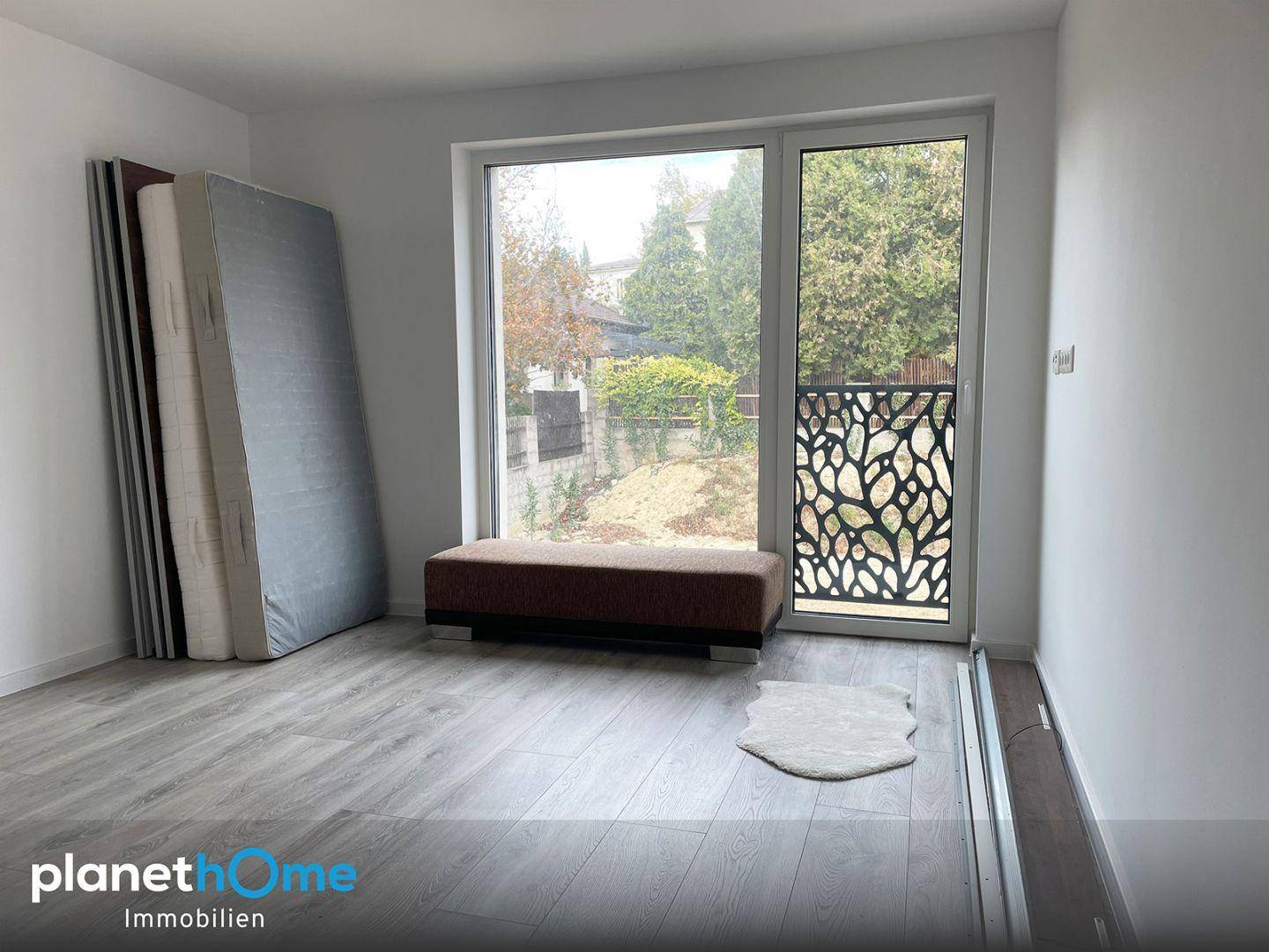 Schlafzimmer mit großem Fenster, französischem Balkon und Blick auf den Garten.