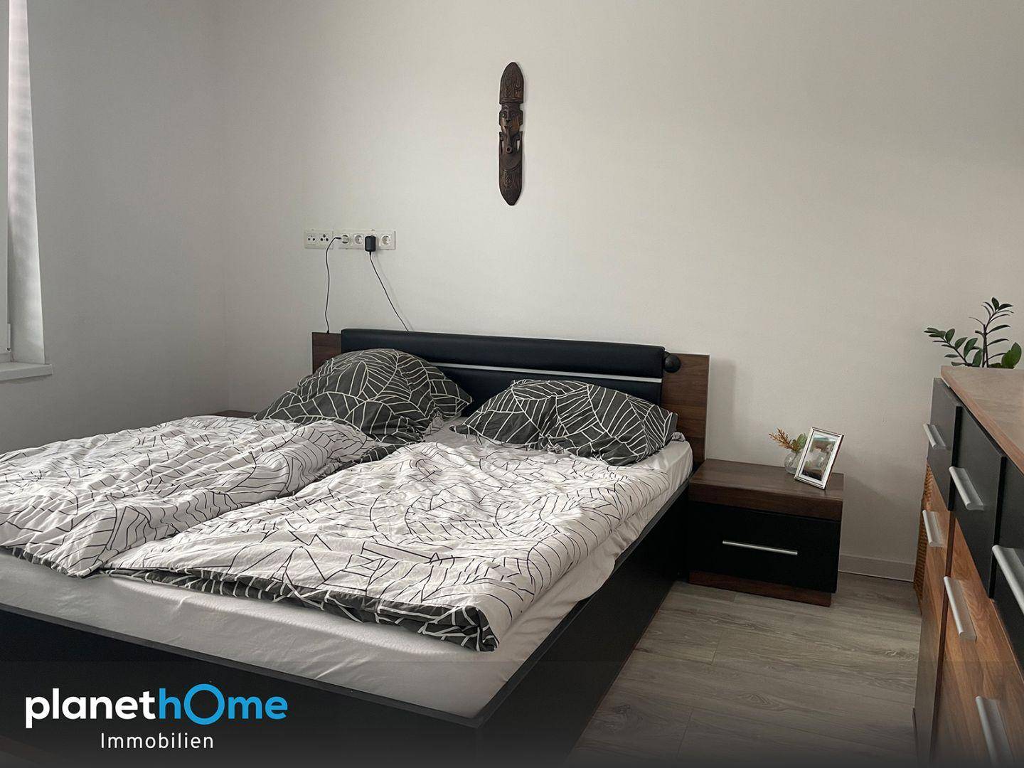 Schlafzimmer mit Doppelbett, Nachttischen und Laminatboden in hellem Holzdekor.