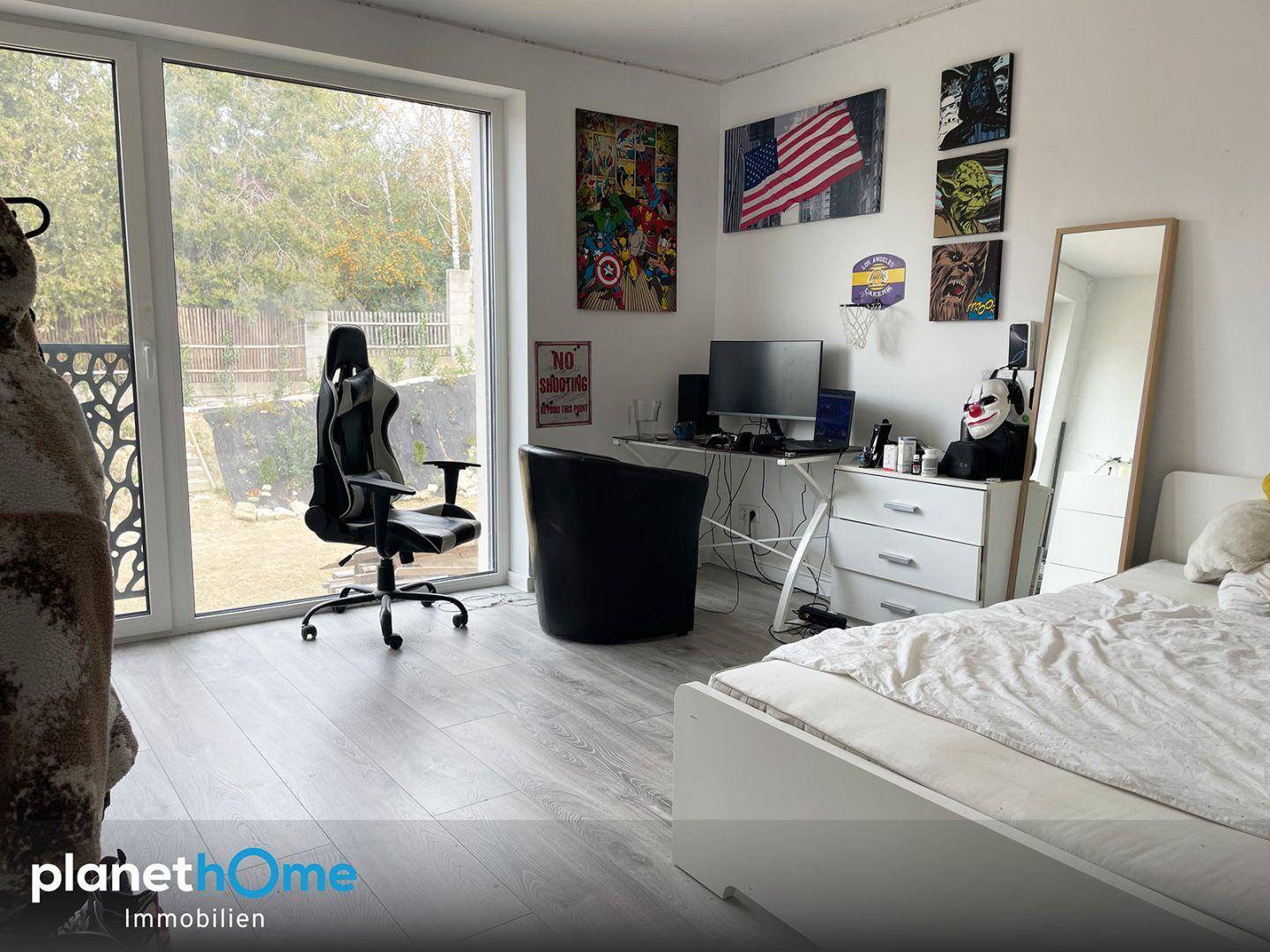 Schlafzimmer, das als Büro genutzt wird, mit Schreibtisch, Gaming-Stuhl und Gartenzugang.