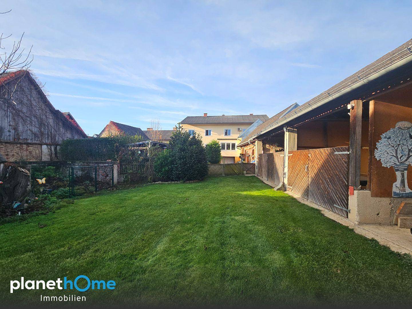 Großer, gepflegter Gartenbereich mit Rasenfläche und Nebengebäude, umgeben von weiteren Wohnhäusern.