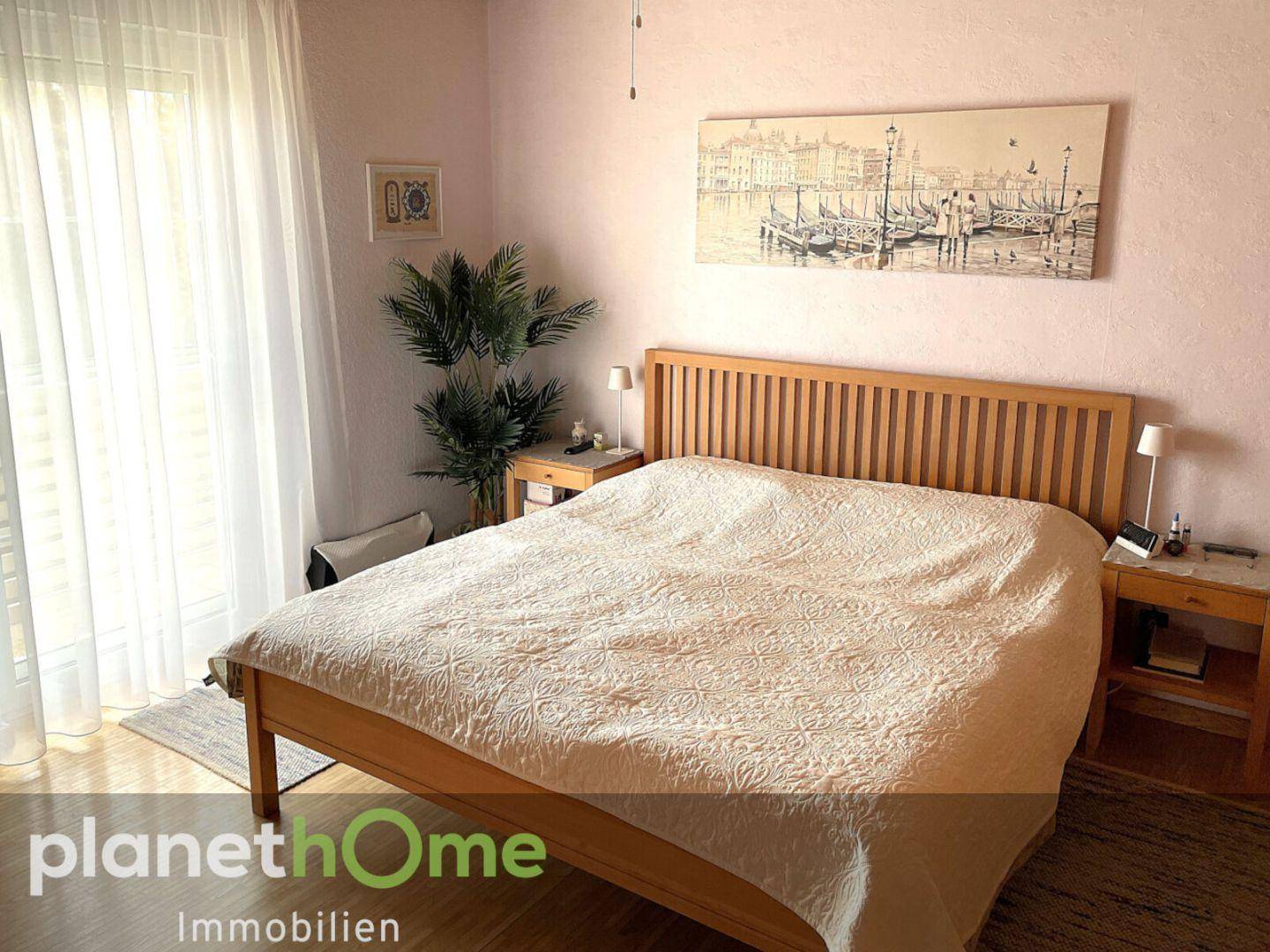 Schlafzimmer mit hellem Holzbett, Parkettboden und Zugang zu einem Balkon oder Terrasse.