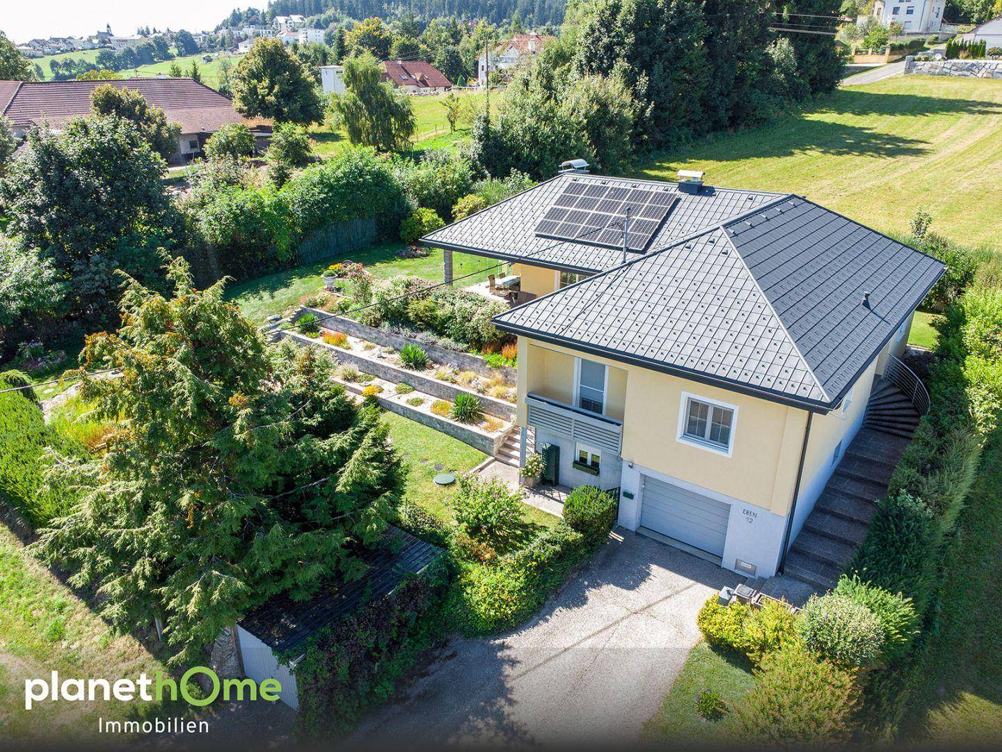 Luftaufnahme des Hauses mit Garage, Auffahrt und gepflegtem Gartenbereich.