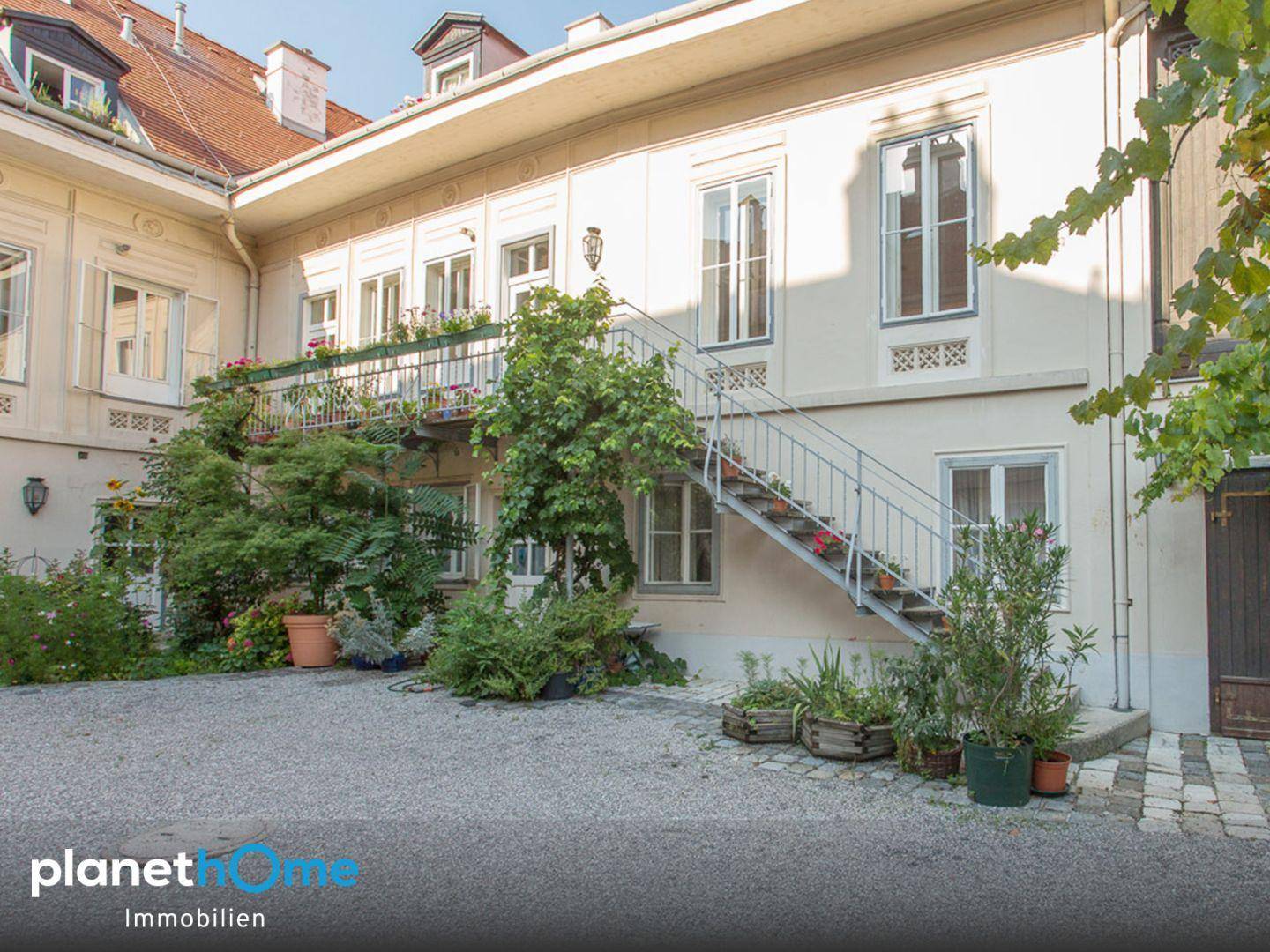 Heller Innenhof mit Kiesfläche, üppiger Bepflanzung und einer eleganten Außentreppe.