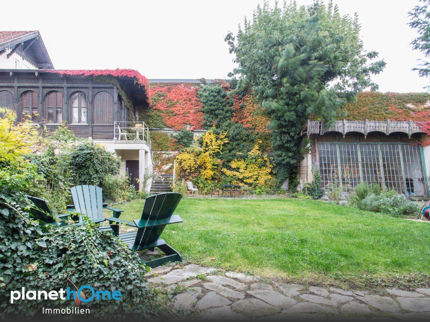 Grüner Garten mit Sitzgelegenheiten und einem von Efeu bewachsenen historischen Gebäude.