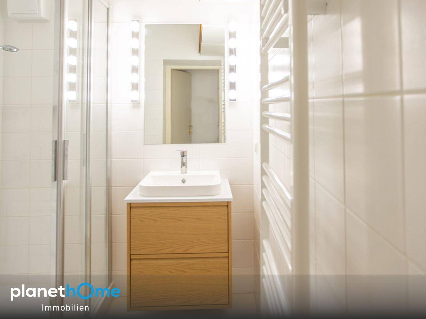Modernes Badezimmer mit Einzelwaschbecken, Spiegelschrank und beheiztem Handtuchhalter.