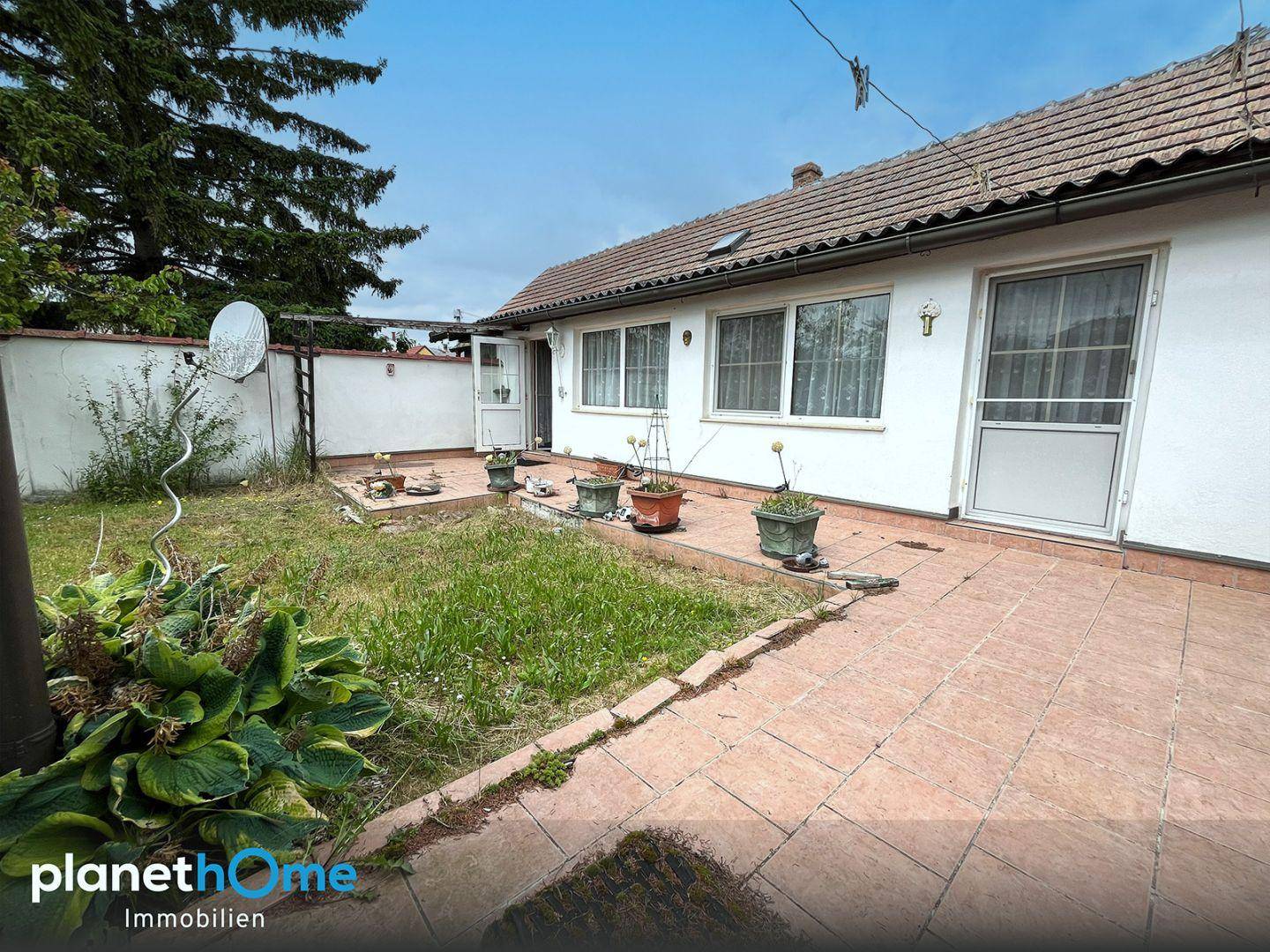 Hinterhof mit gepflasterter Terrasse und Rasenfläche, ideal für entspannte Stunden im Freien.