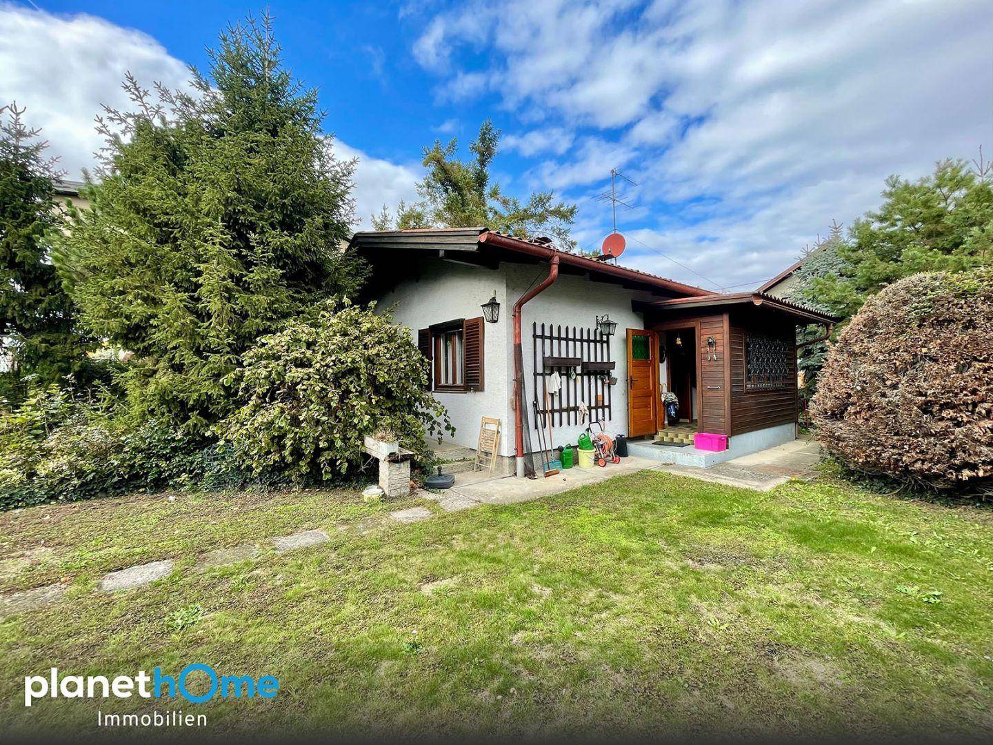Einfamilienhaus mit Vorgarten, überdachtem Eingangsbereich und viel Grün in der Umgebung.