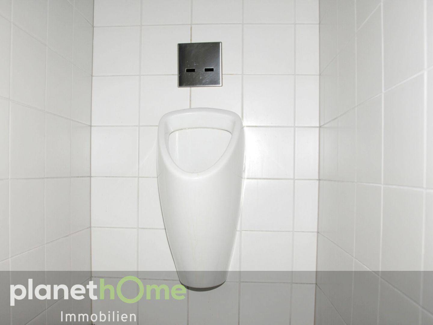 Sauberes Urinal in einem gefliesten WC-Bereich, passend für gewerbliche Nutzung.