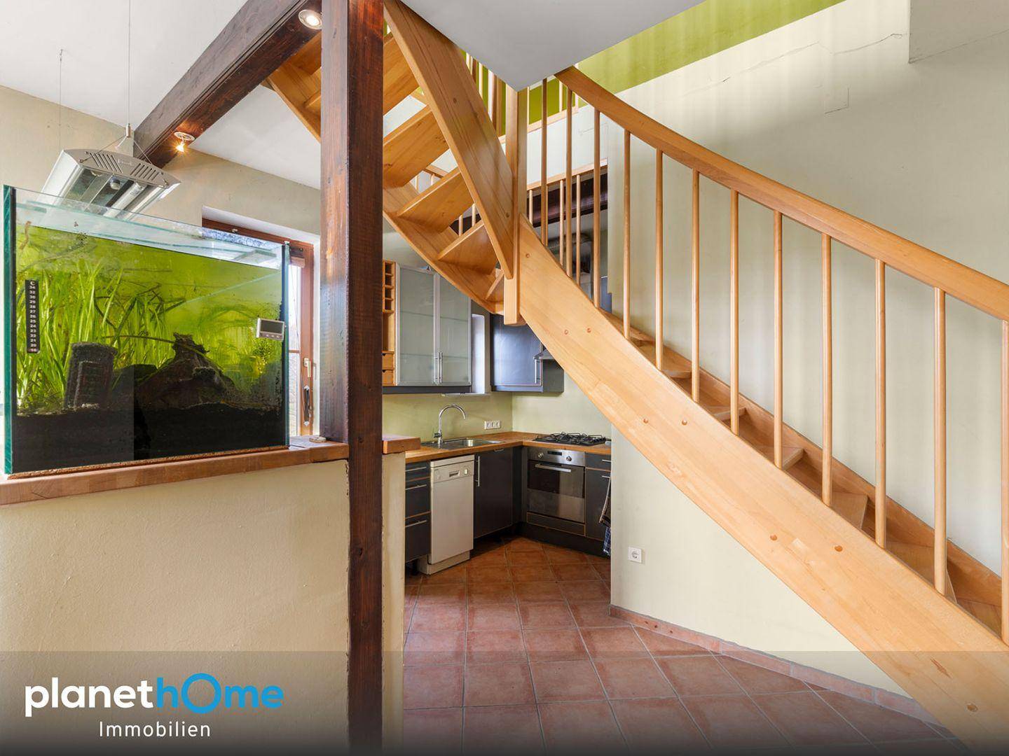 Kleine Küchenzeile unter der Holztreppe mit Spüle und Kochfeld, ideal für eine Einliegerwohnung.