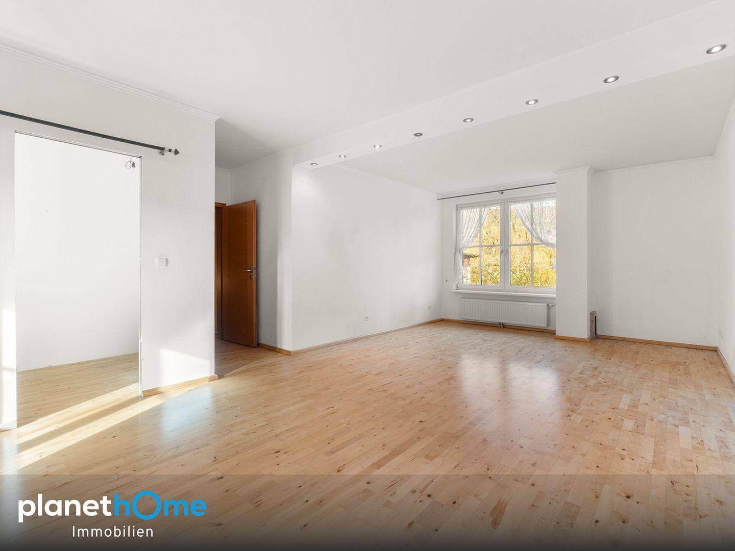 Geräumiger, heller Raum mit Parkettboden und großem Fenster, ideal für Wohn- oder Schlafbereich.