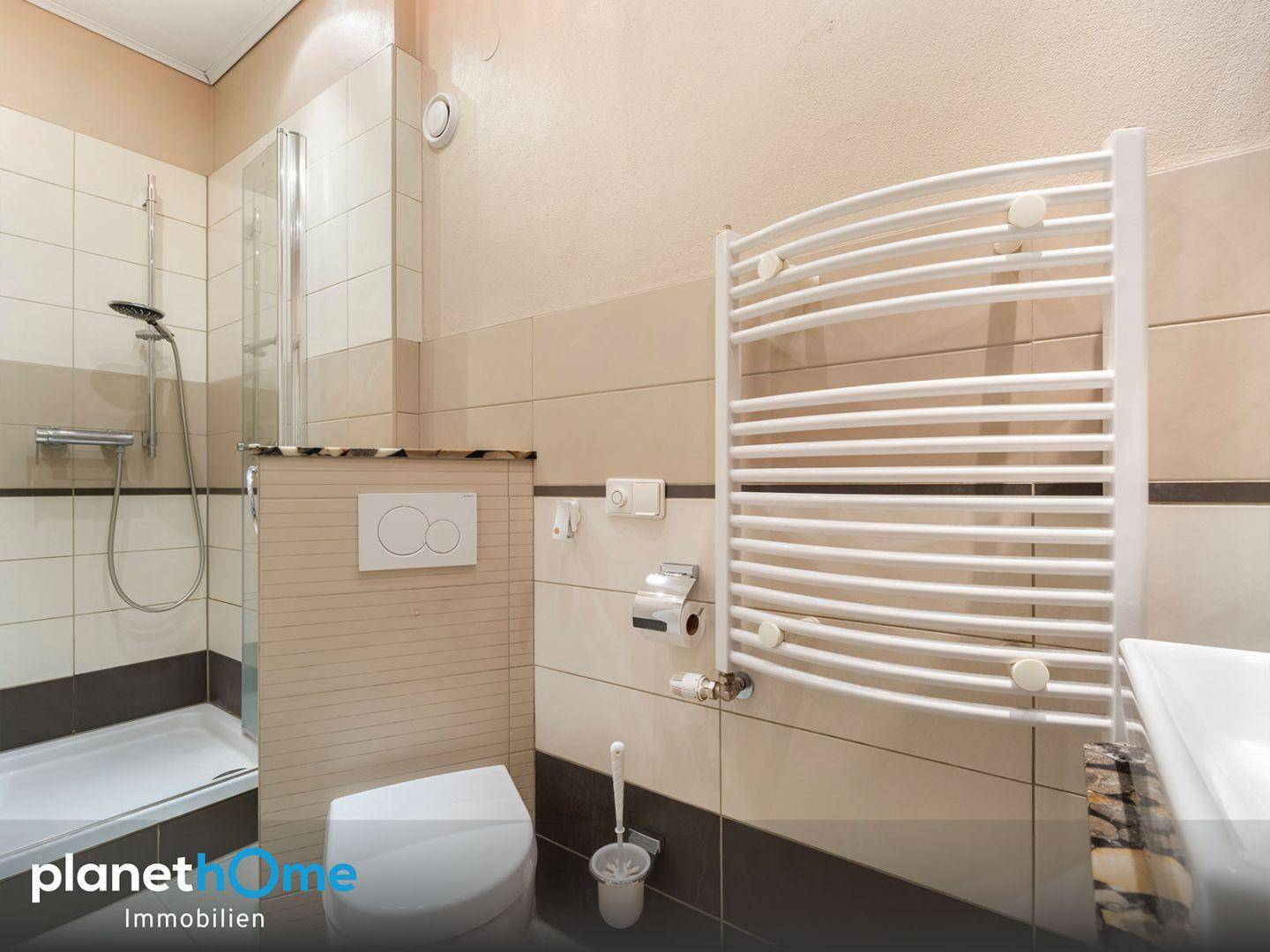 Modernes Badezimmer mit Duschkabine, Wand-WC und beheiztem Handtuchhalter.