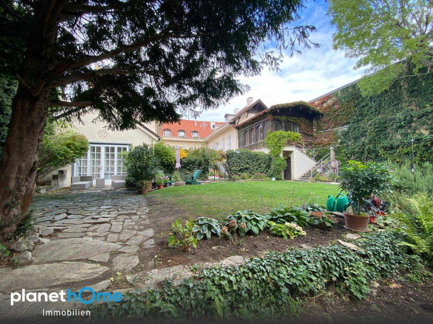 Großer, gepflegter Garten mit Rasenfläche, altem Baumbestand und Zugang zum historischen Haus.