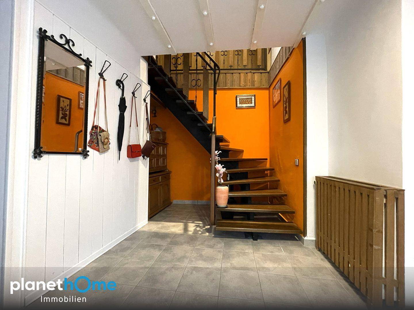 Heller Eingangsbereich mit Fliesenboden, Holzvertäfelung und einer Treppe ins Obergeschoss.