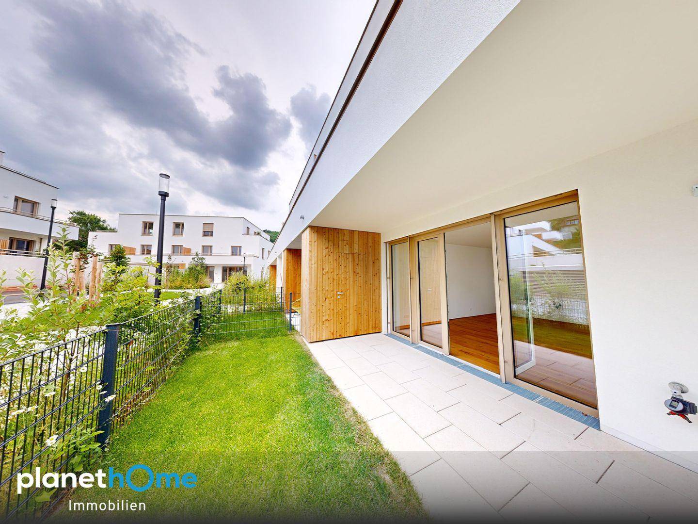 Moderne Terrasse mit Fliesenboden und Zugang zu einem neuen Gebäude mit Holzverkleidung.