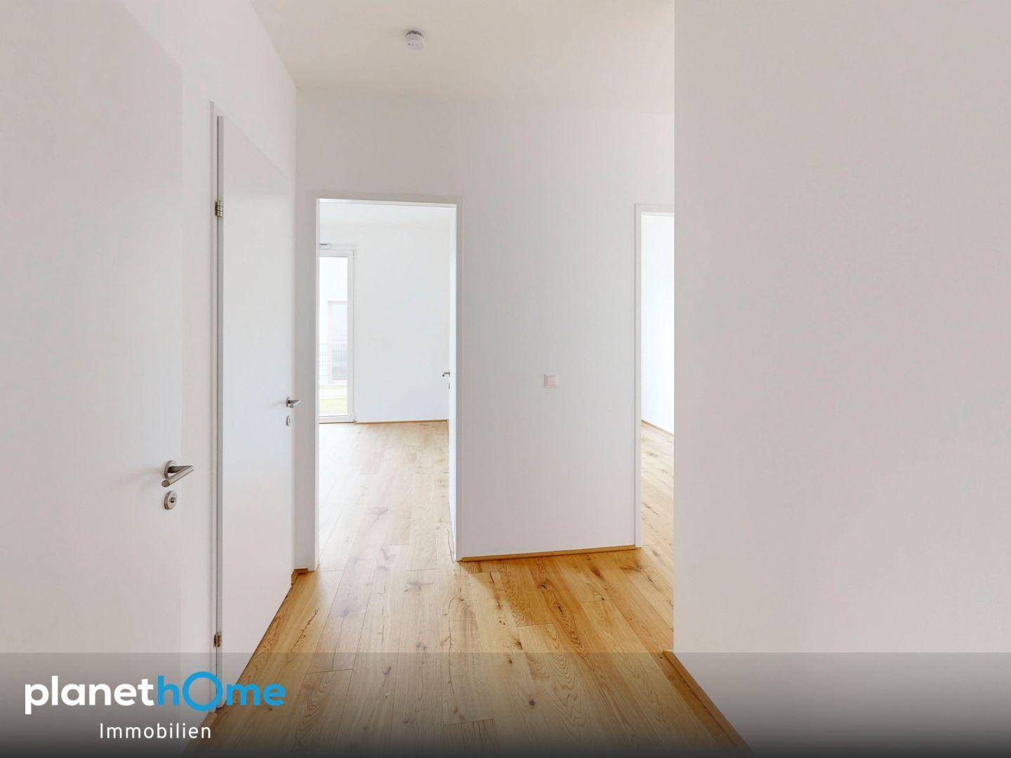 Heller Flur mit Holzboden und Türen zu verschiedenen Räumen in einem modernen Neubau.
