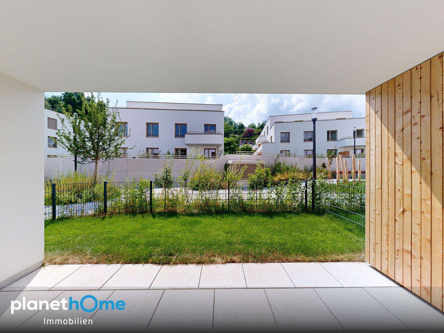 Blick von der Terrasse auf den Gemeinschaftsgarten und die modernen Wohngebäude.
