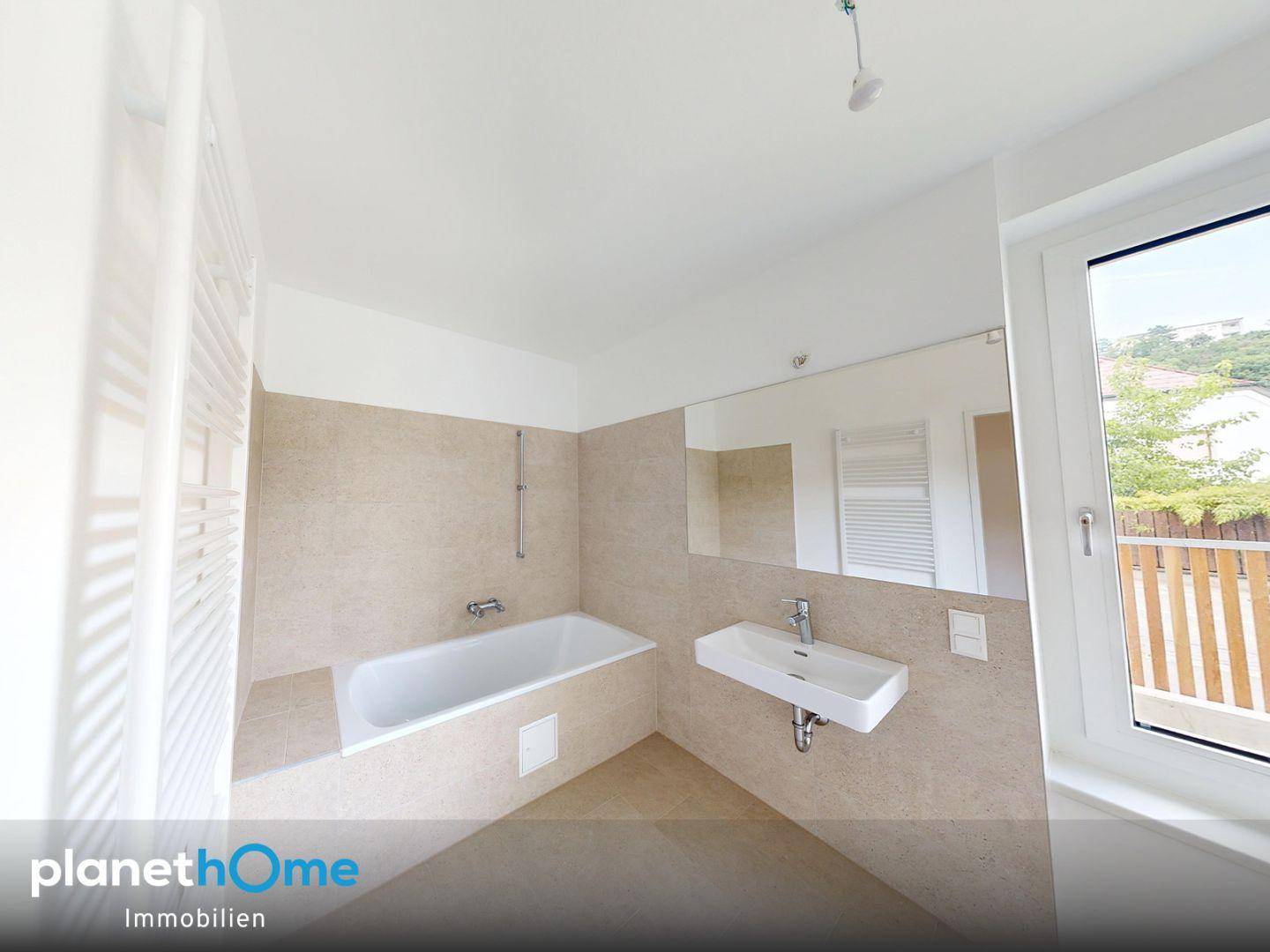 Modernes Badezimmer mit Badewanne, Waschbecken, Fliesen und beheiztem Handtuchhalter.
