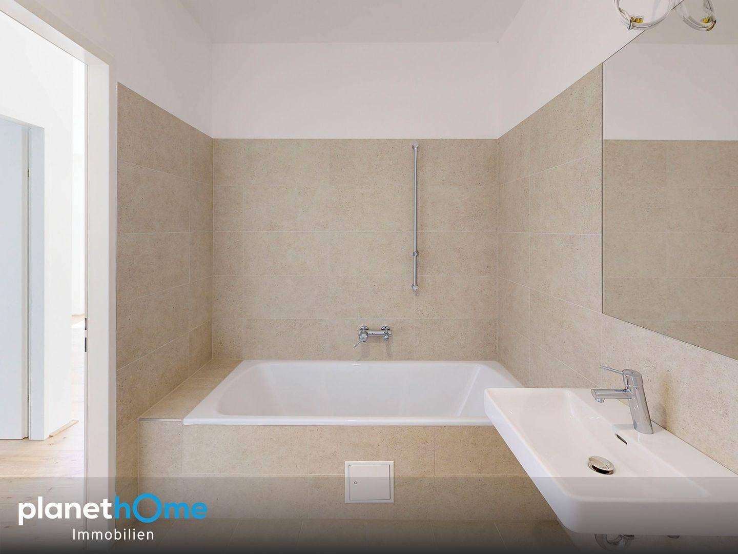 Modernes Badezimmer mit beigefarbenen Fliesen, integrierter Badewanne und Einzelwaschbecken.