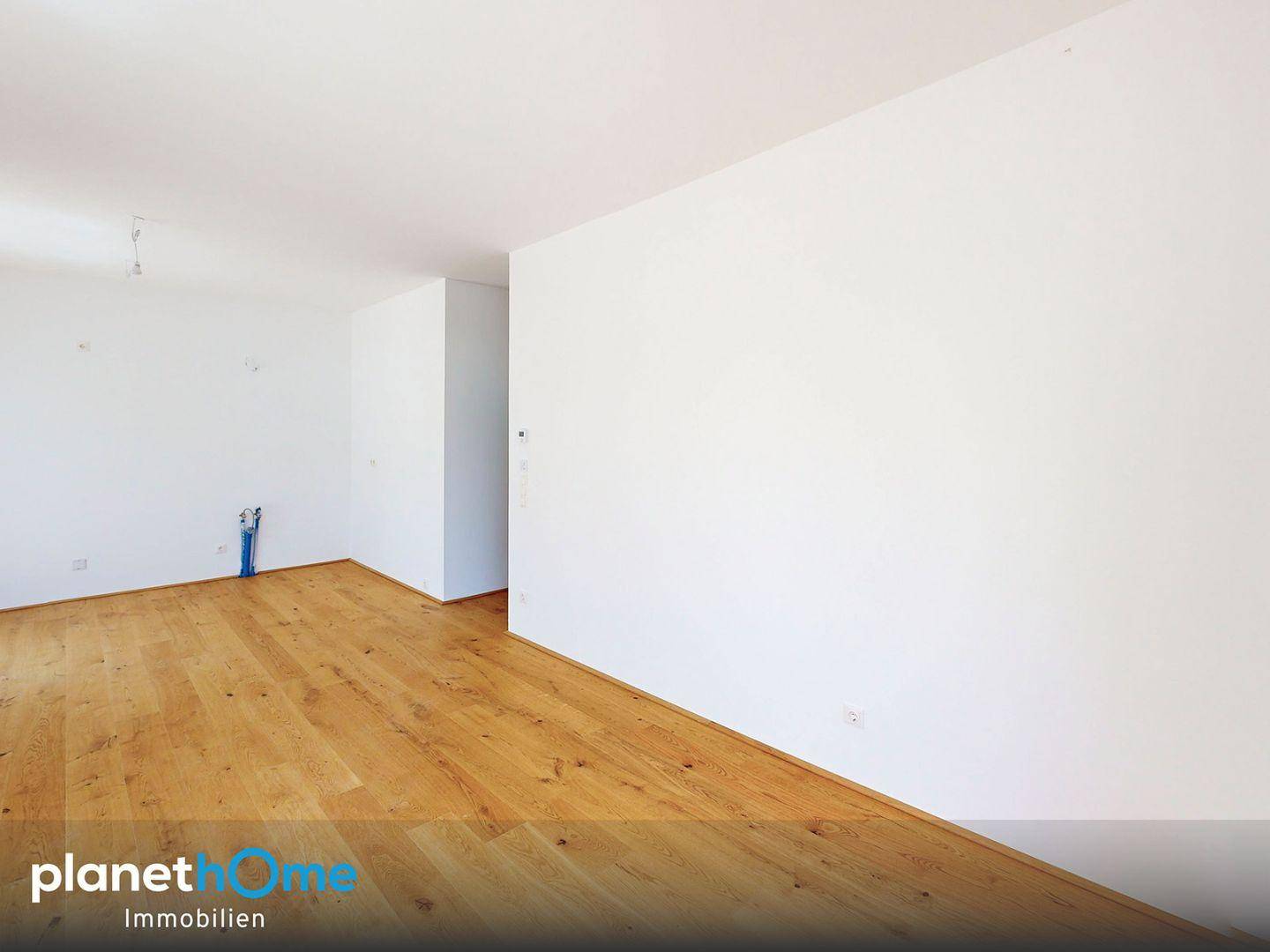Leerer Raum mit Holzboden und sichtbaren Anschlüssen für zukünftige Installationen.