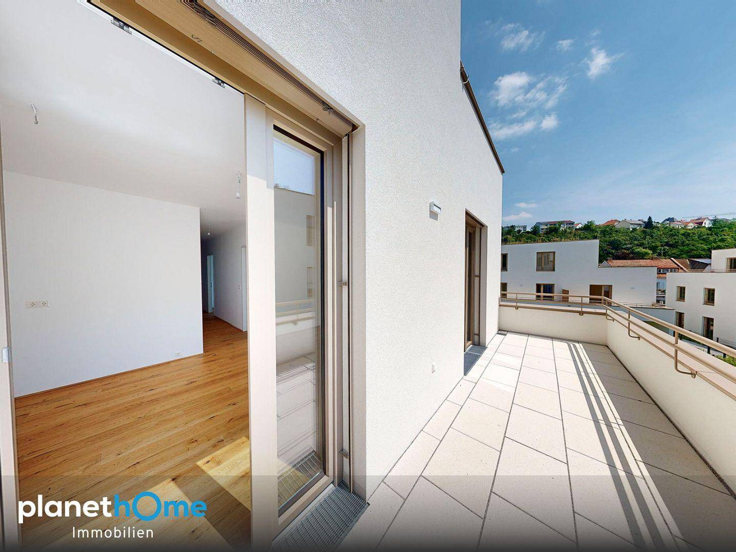 Geräumiger Balkon mit Fliesenboden und Blick auf die umliegende Wohngegend und Hügel.