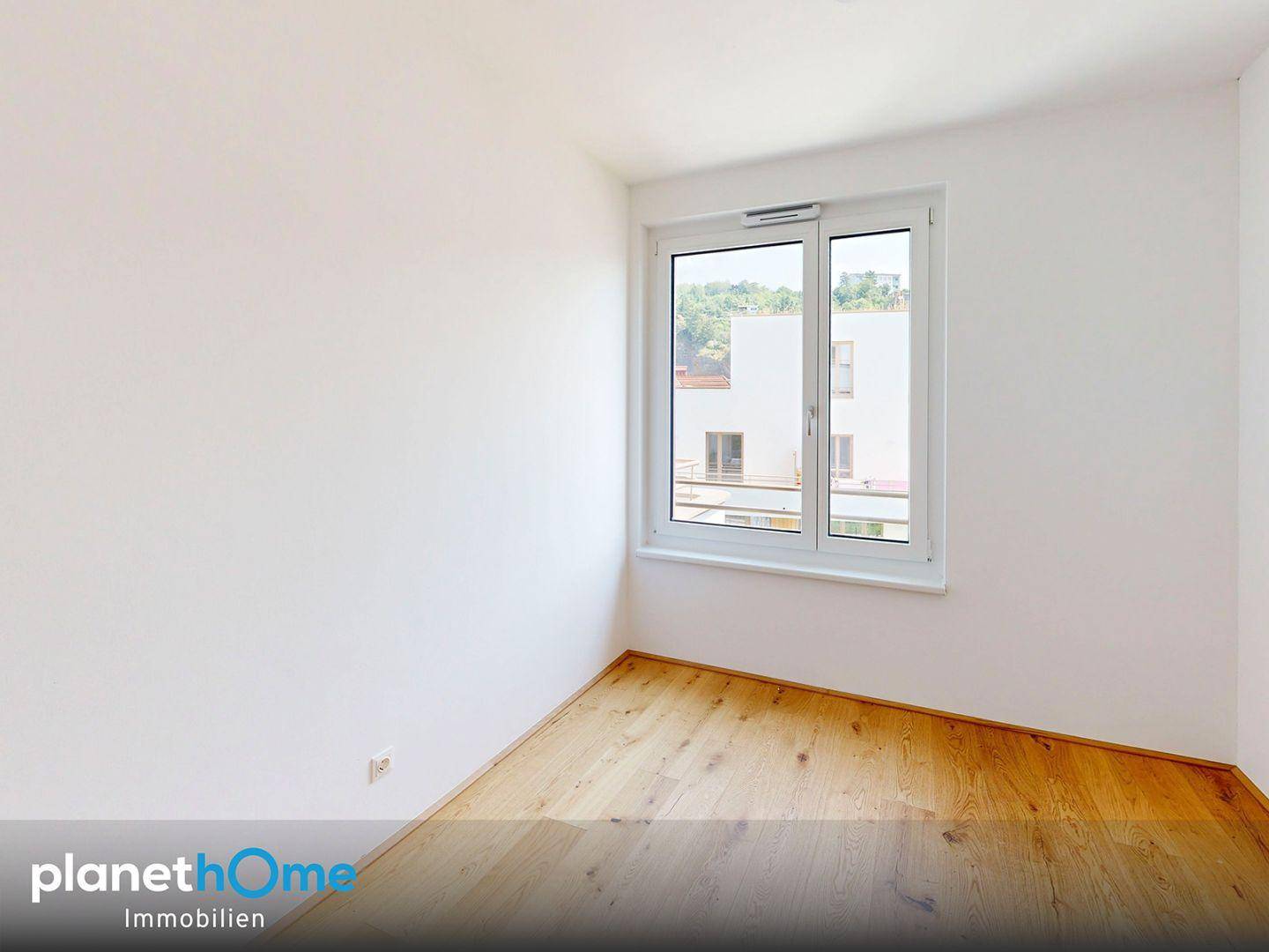 Geräumiges Schlafzimmer mit Parkettboden und viel Tageslicht durch das große Fenster.