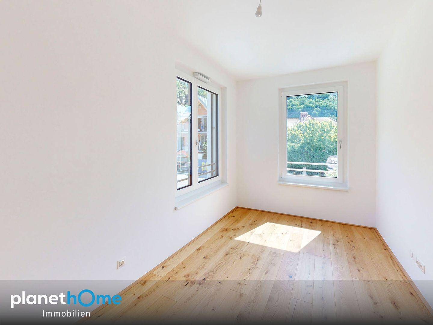 Ruhiges Zimmer mit einem großen Fenster und Parkettboden, bietet viel natürliches Licht.