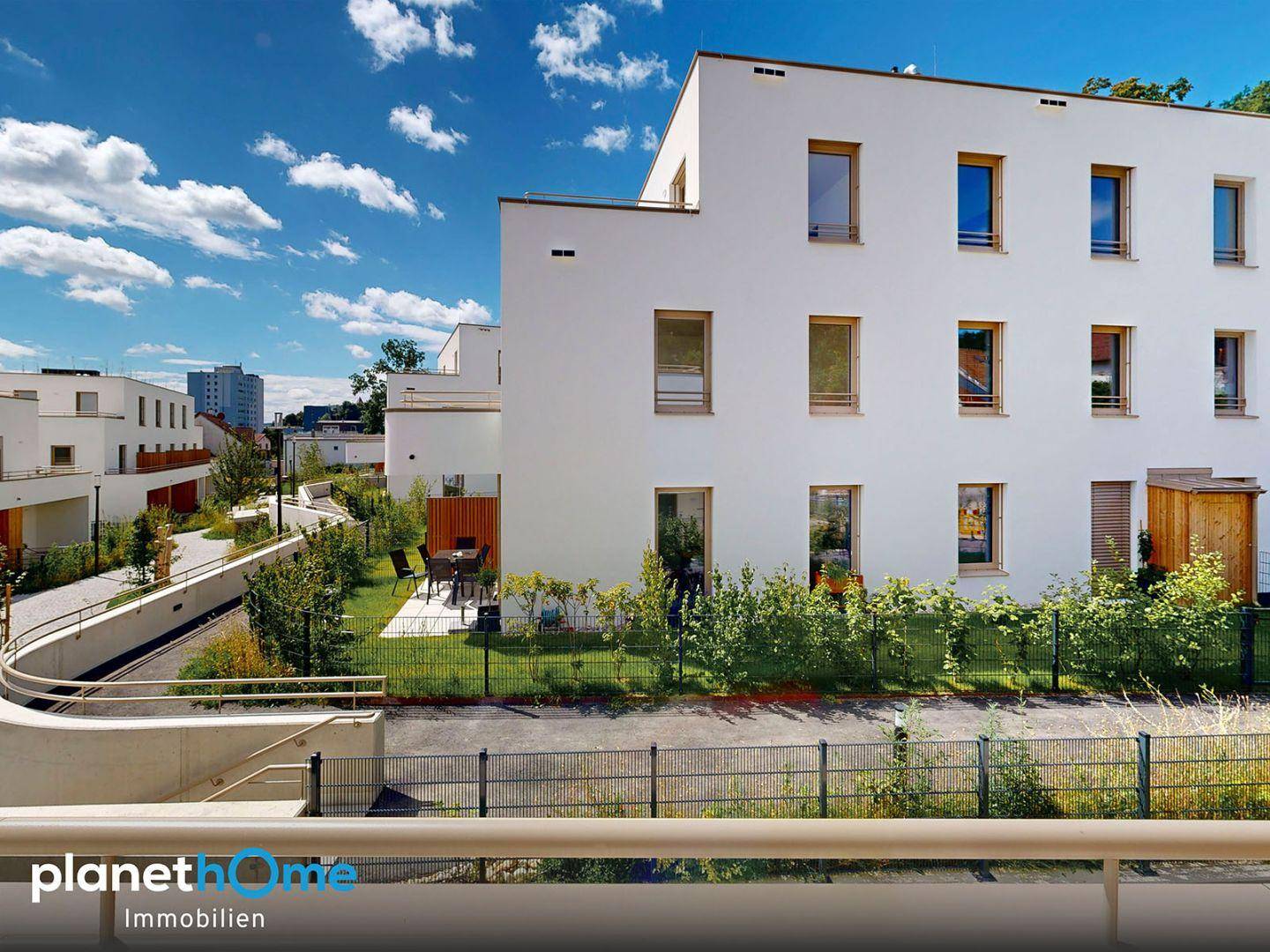 Ansicht der modernen Wohnanlage mit privatem Gartenbereich und Sitzgelegenheit.