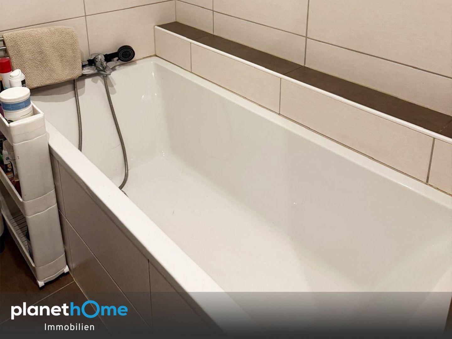 Nahaufnahme der Badewanne in einem hell gefliesten Badezimmer.