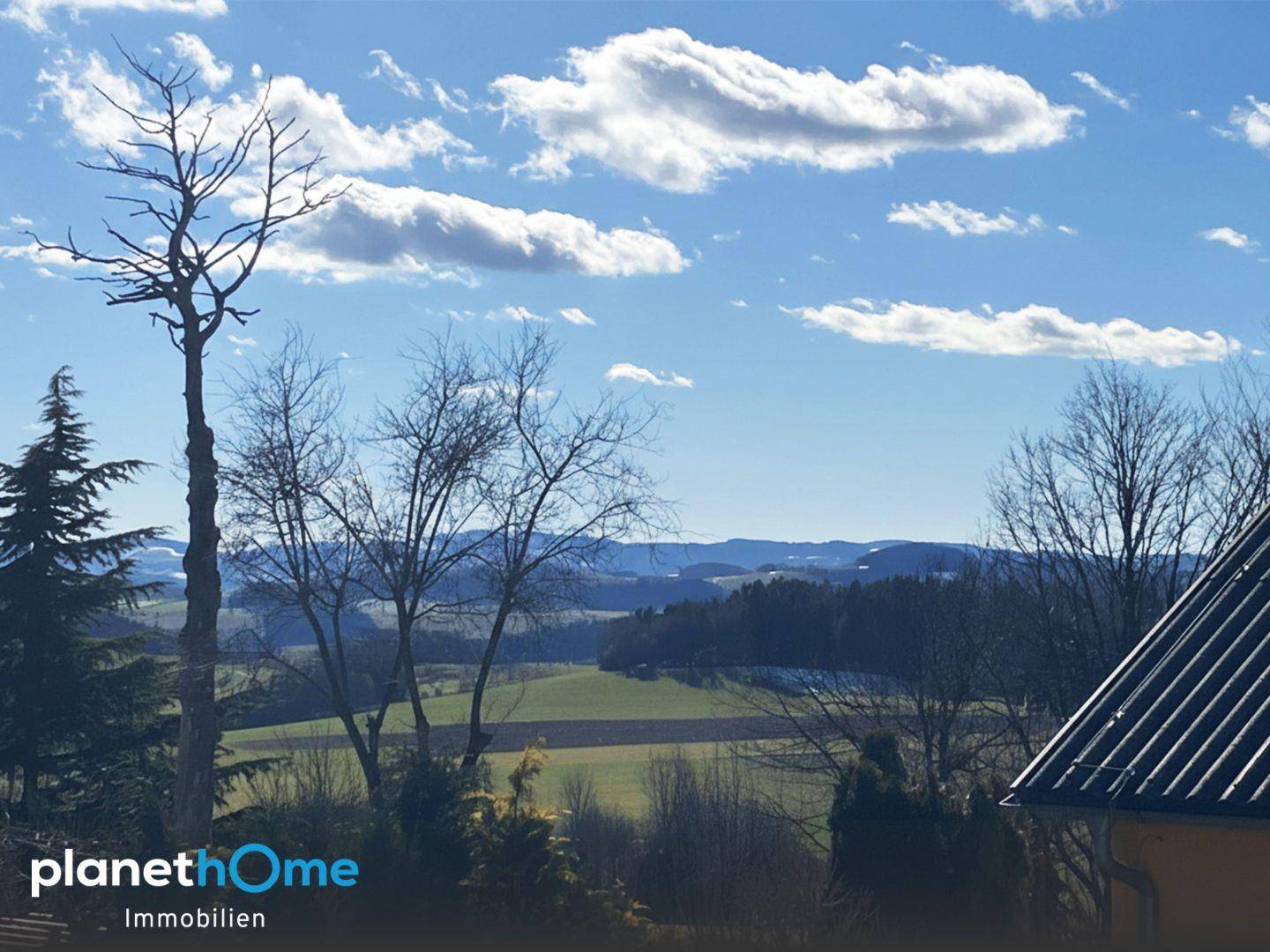 Weitläufiger Blick über die hügelige Landschaft mit Feldern und Wäldern.