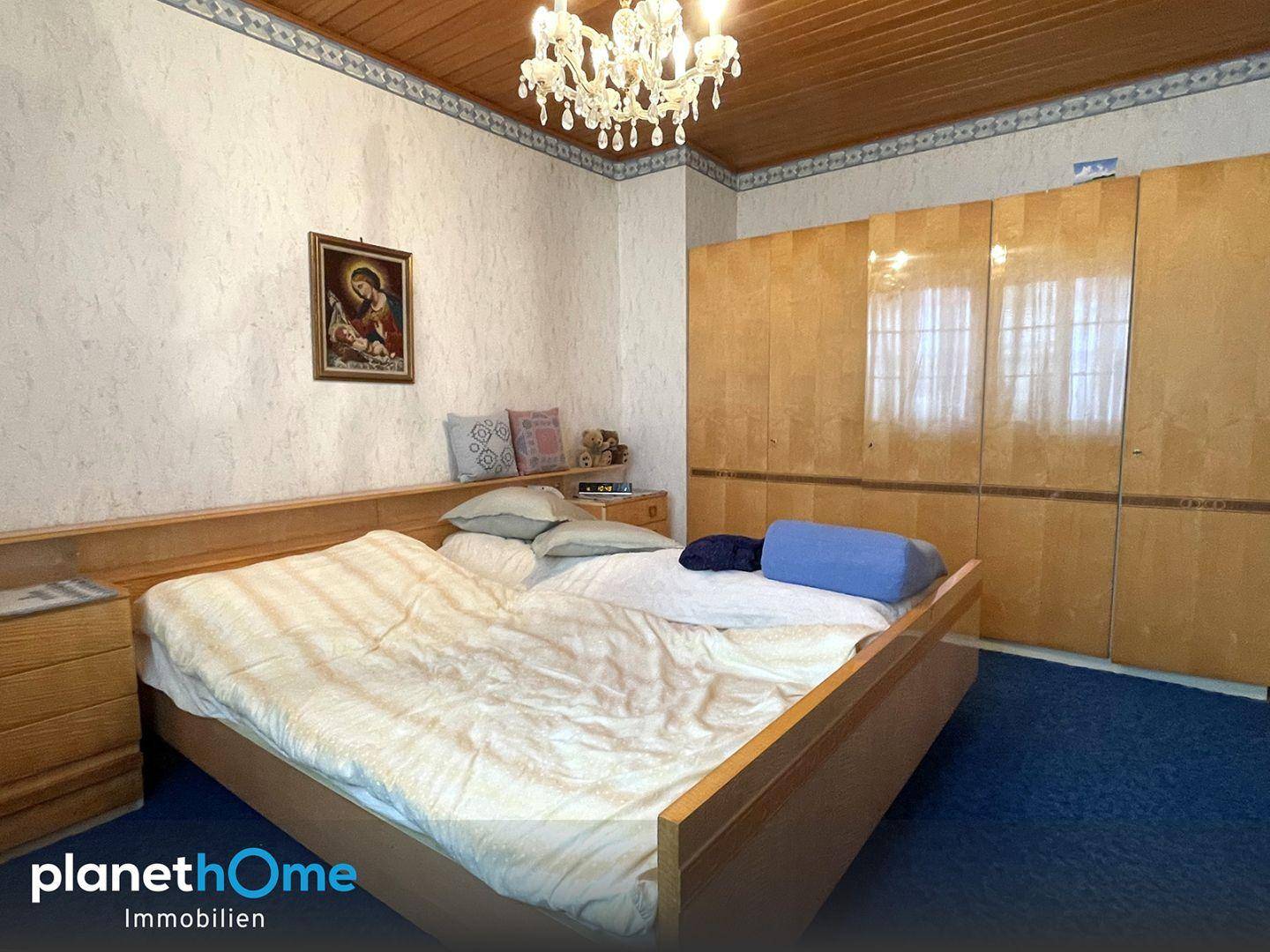 Schlafzimmer mit Doppelbett, blauer Auslegware und Holzdecke in traditionellem Stil.