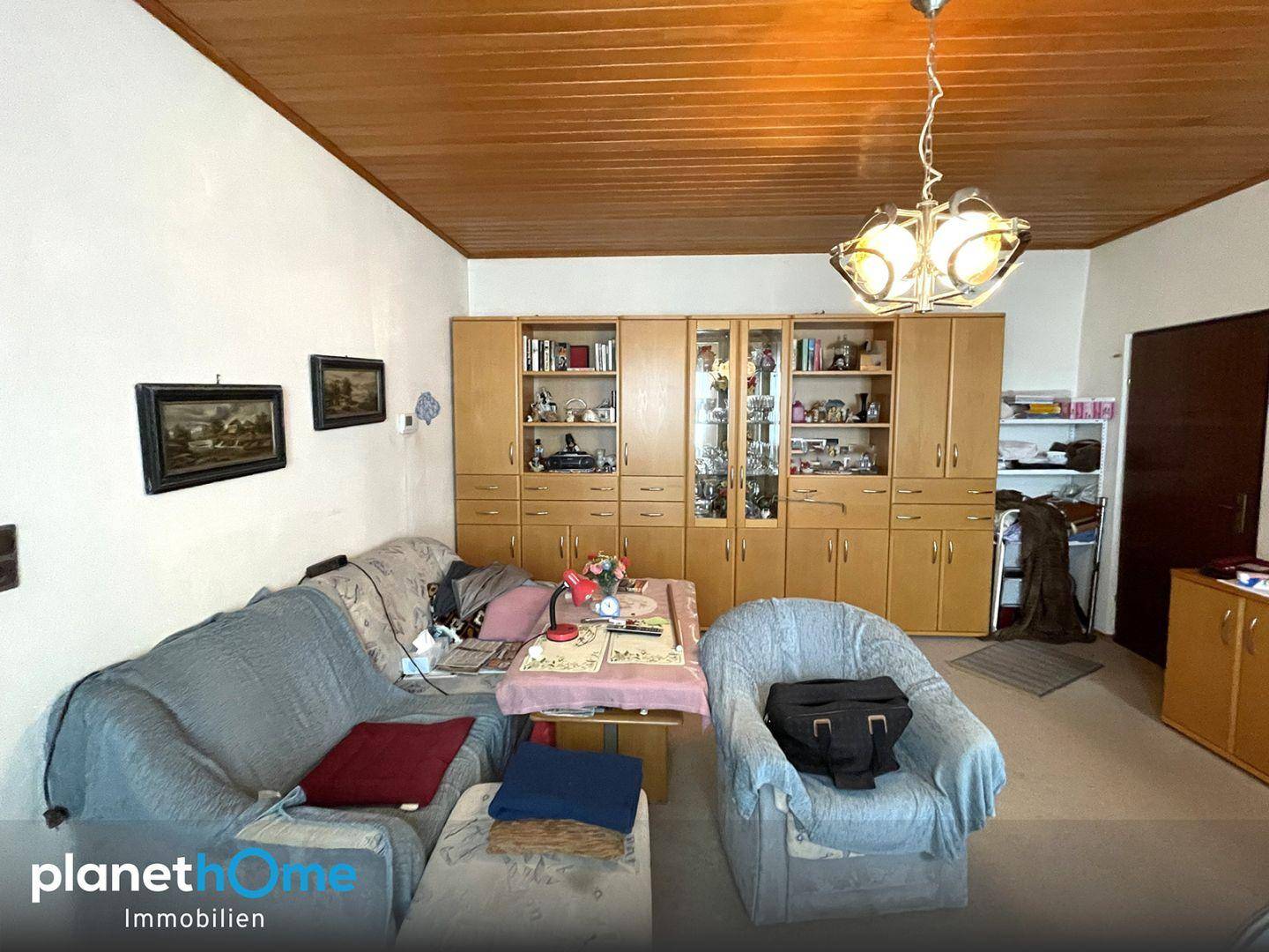 Gemütliches Wohnzimmer mit Holzdecke, Teppichboden und traditionellen Möbeln.